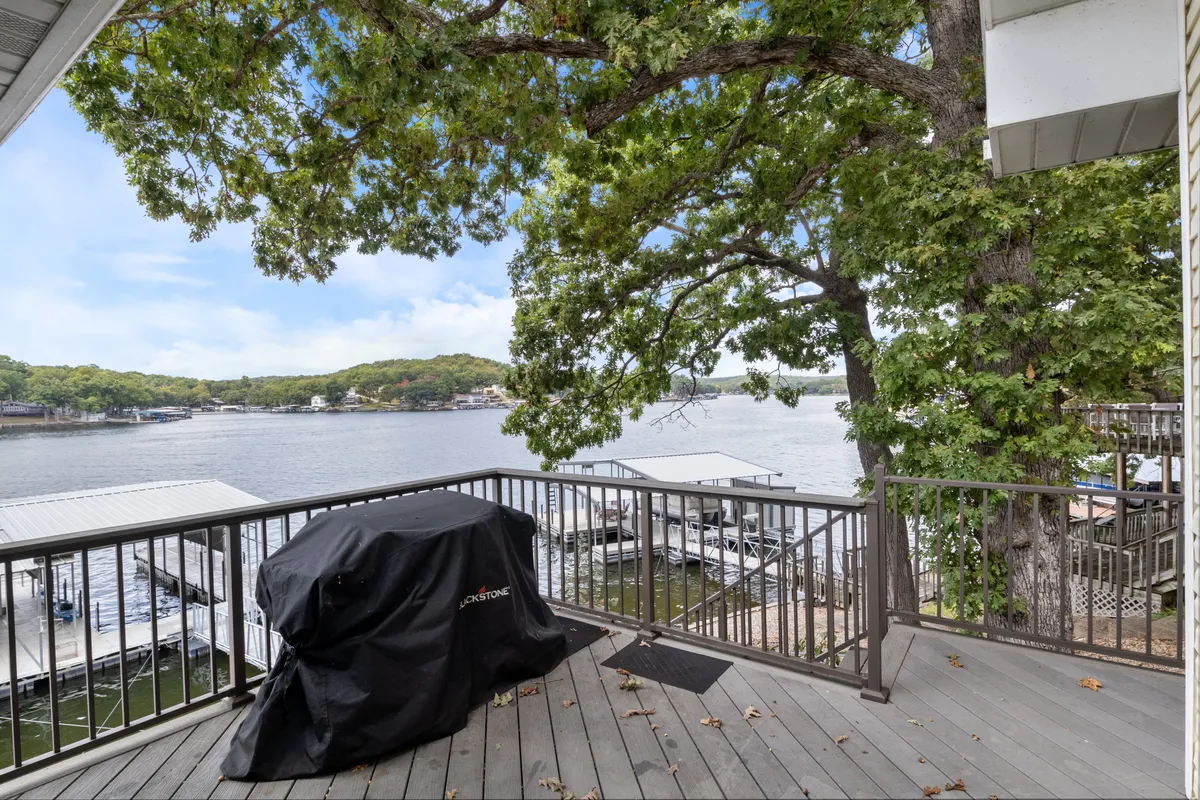 A serene deck area sits under the shade of large trees, with a grill and sweeping views of the lake. The intimate space is perfect for quiet morning coffee or evening chats as the sun sets.