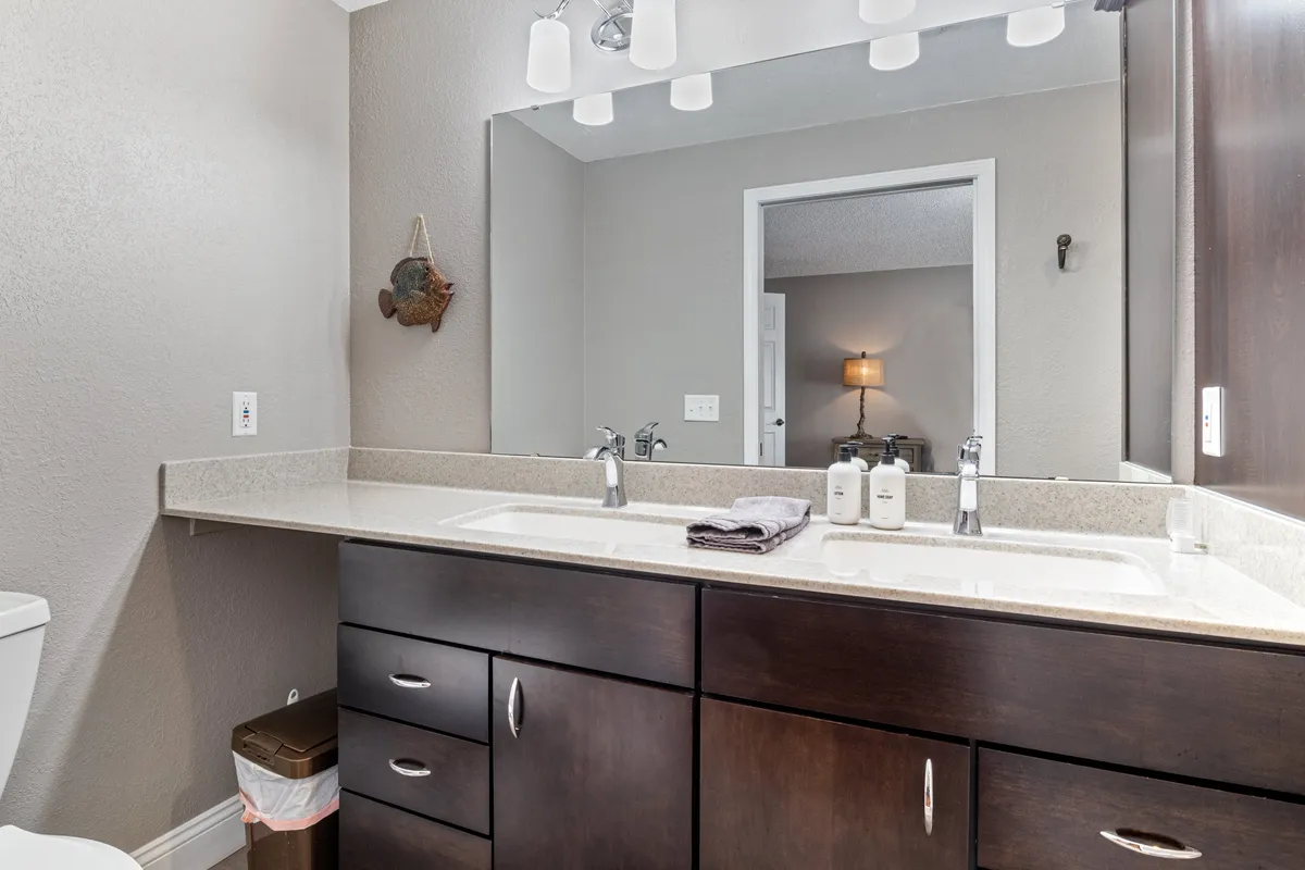 A modern laundry area with a double sink, large mirror, and dark cabinetry. The space is organized and functional, suggesting convenience for families needing to handle laundry during their stay.