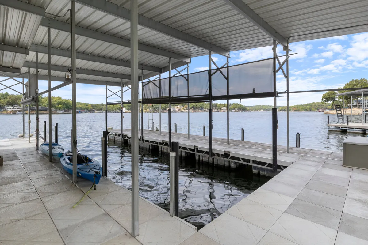 This image captures a lively lakeside scene featuring kayaks on the dock, glimmering water, and a scenic view beyond. The dock is prominently positioned, highlighting easy access for water activities and social gatherings. The overall feeling is active yet relaxed, suggesting both adventure and leisure.