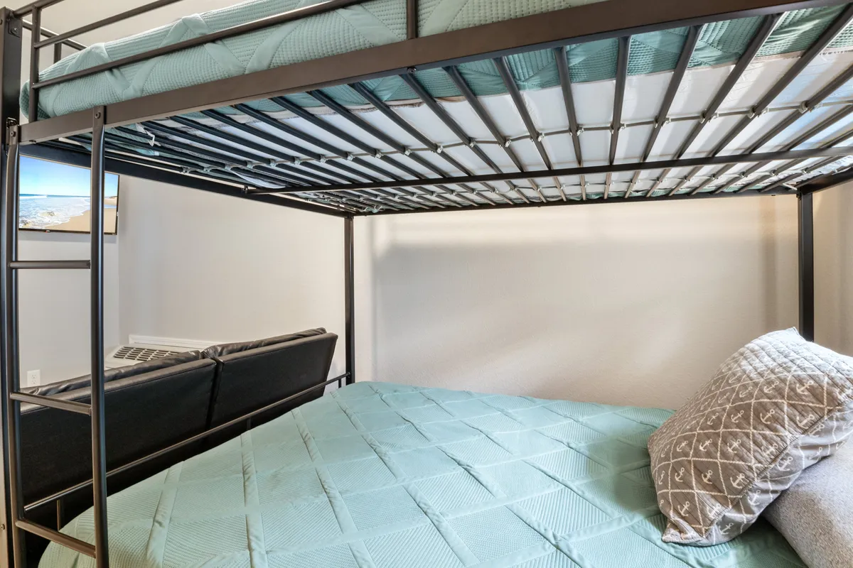 A family-oriented lounge area with a bunk bed, sofa, decorative pillow, and a wall-mounted TV. The layout suggests a place where families can gather, relax, and share stories or movie nights, catering to both children and adults.